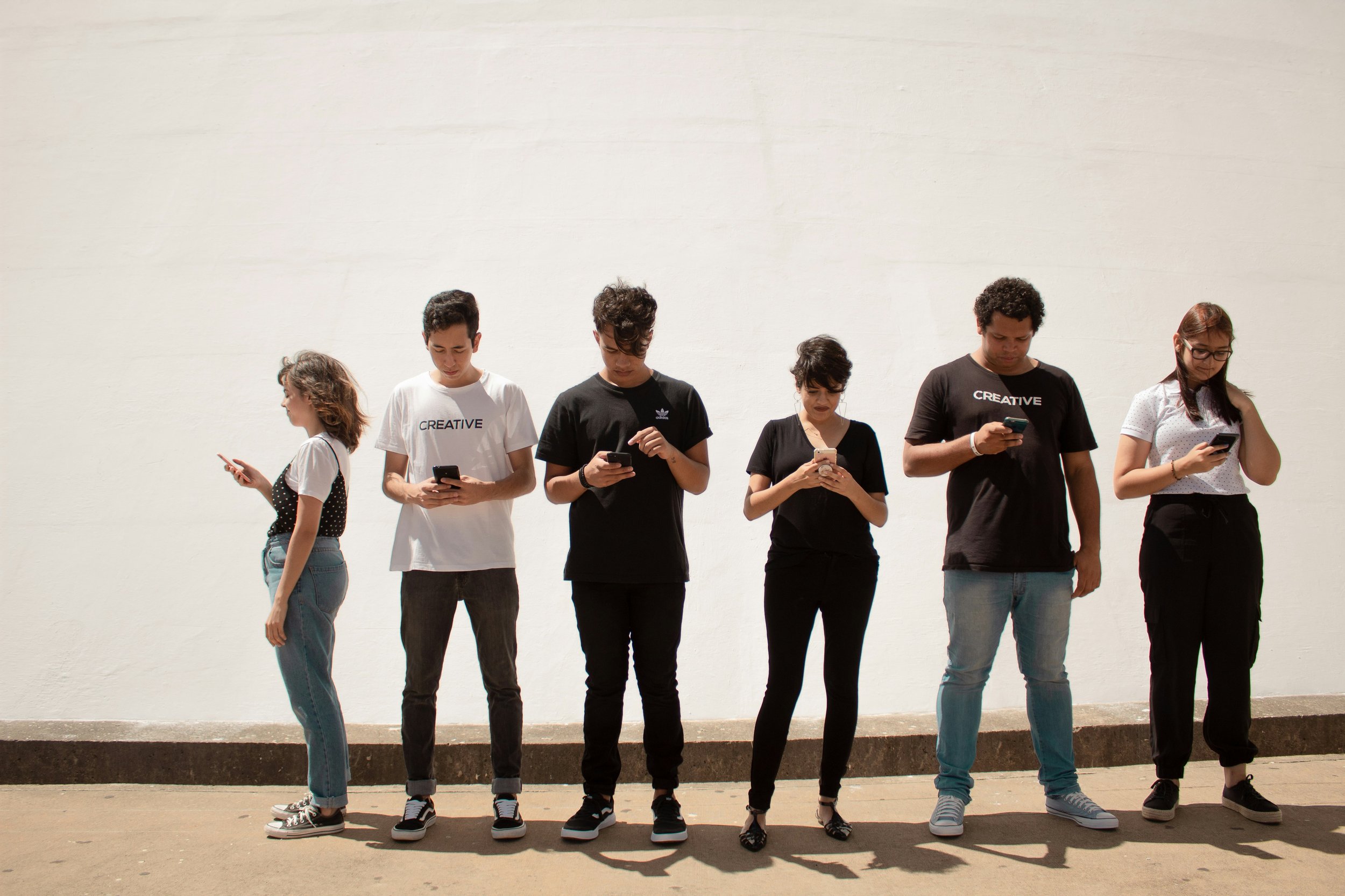Group of young people using smartphones outdoors.