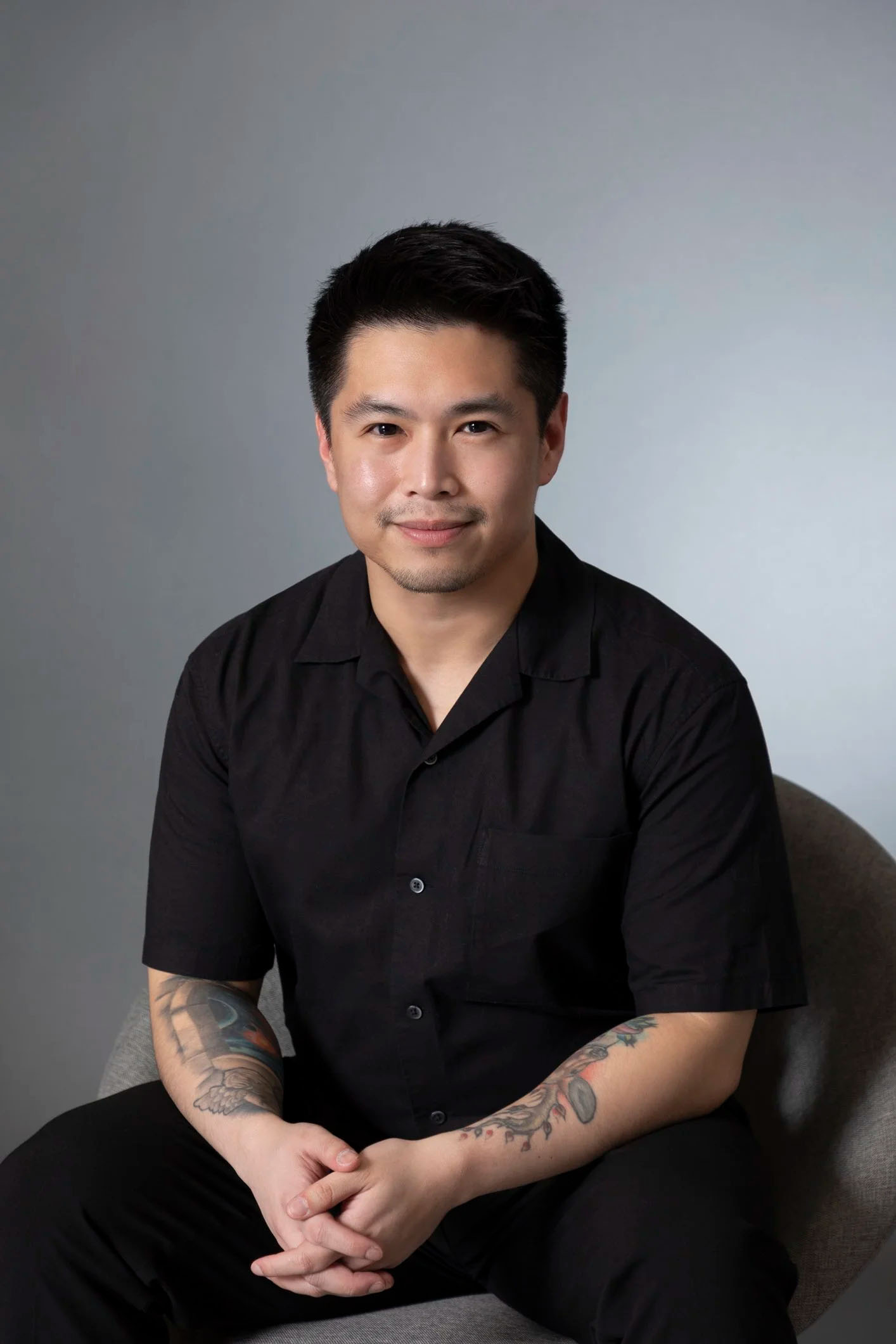 Man with tattoos sitting on a chair.